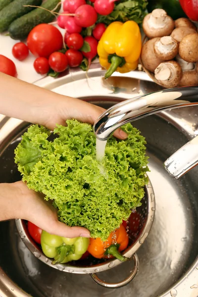 Las manos de mujer lavando hortalizas en el fregadero en la cocina — Foto de Stock