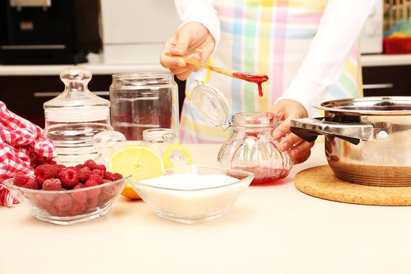 Woman cooking raspberry jam in kitchen — Stock Photo, Image