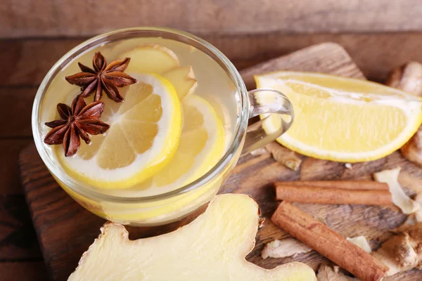 Tazza di bevanda allo zenzero con limone sul tagliere su tavolo in legno su fondo parete in legno — Foto Stock