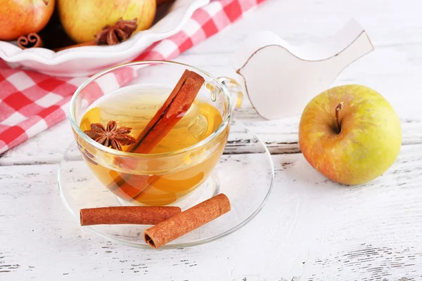 Apple sari dengan kayu manis tongkat dan apel segar di atas meja kayu, di latar belakang cerah — Stok Foto