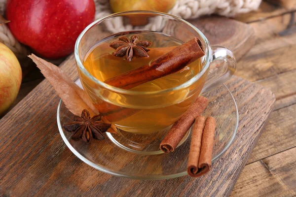 Composition of  apple cider with cinnamon sticks, fresh apples, warm scarf and autumn leaves on wooden background — Stock Photo, Image