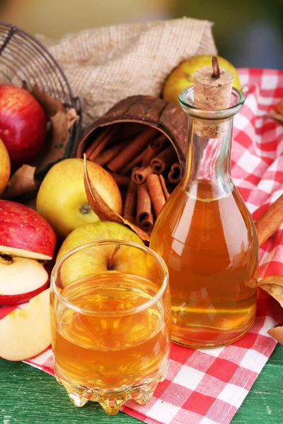 Komposisi sari apel dengan tongkat kayu manis, apel segar dan daun musim gugur di latar belakang kayu — Stok Foto