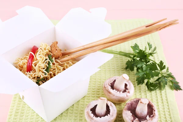 Chinese noodles and sticks in takeaway box on green napkin on pink background — Stock Photo, Image