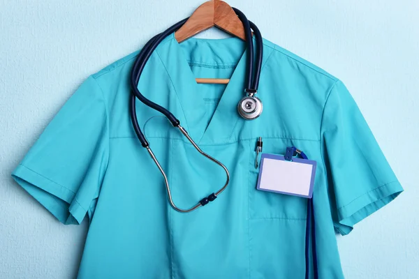 Camisa médica con estetoscopio en percha sobre fondo azul — Foto de Stock