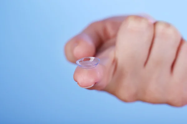 Contact lens on finger on blue background — Stock Photo, Image