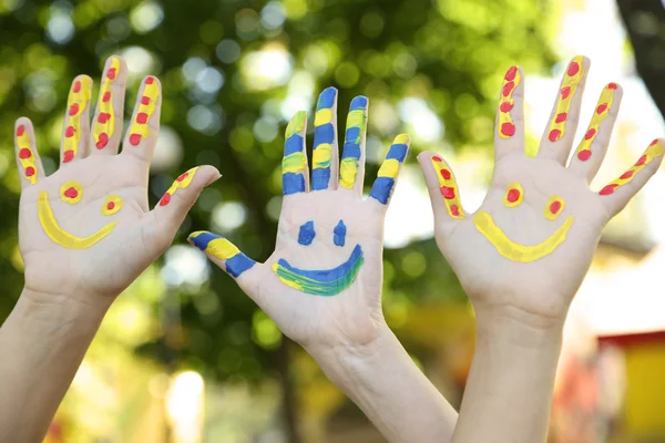 Smiling colorful hands on natural background — Stock Photo, Image