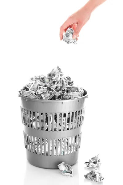 Mão jogando dinheiro na lata de lixo isolado em branco — Fotografia de Stock