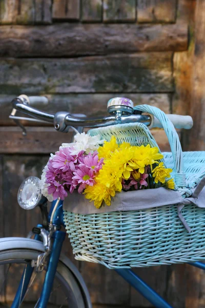 Old bicycle with flowers in metal basket on old brown door background — Stock Photo, Image