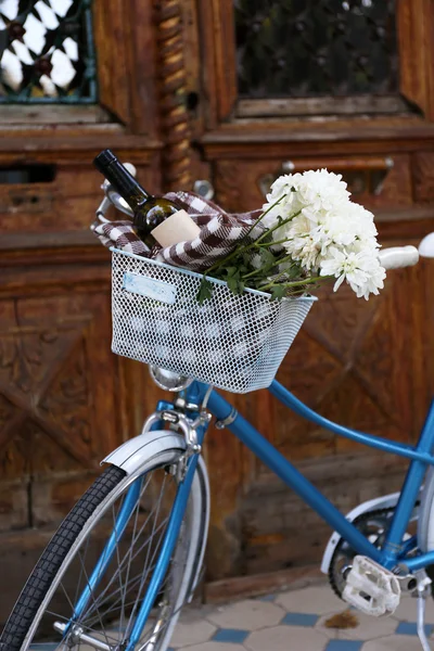 Vecchia bicicletta con fiori in cesto di metallo su sfondo porta marrone — Foto Stock