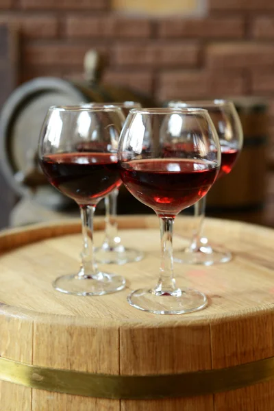 Glasses of wine in cellar with old barrels — Stock Photo, Image
