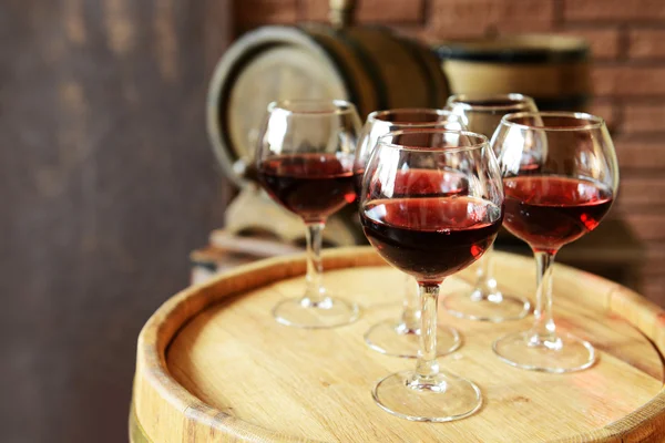 Glasses of wine in cellar with old barrels — Stock Photo, Image