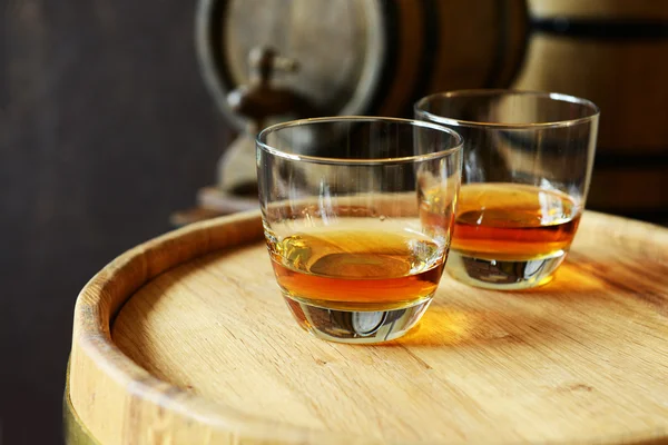 Vasos de brandy en bodega con barriles viejos —  Fotos de Stock