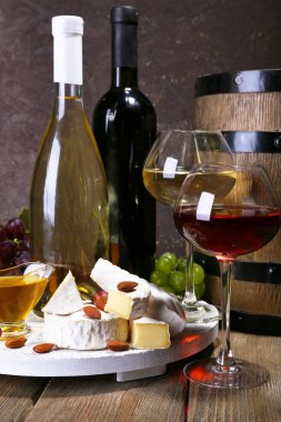 Camembert peyniri, bal, şarap ve stand üzüm ve şarap varil üzerinde kahverengi zemin ahşap masa üzerinde oluşan akşam yemeği