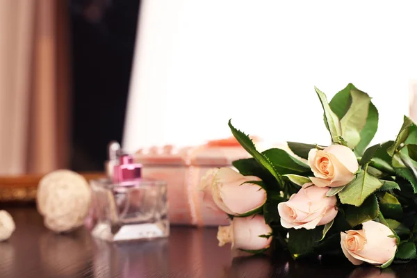 Beautiful roses, perfumes on table near mirror — Stock Photo, Image