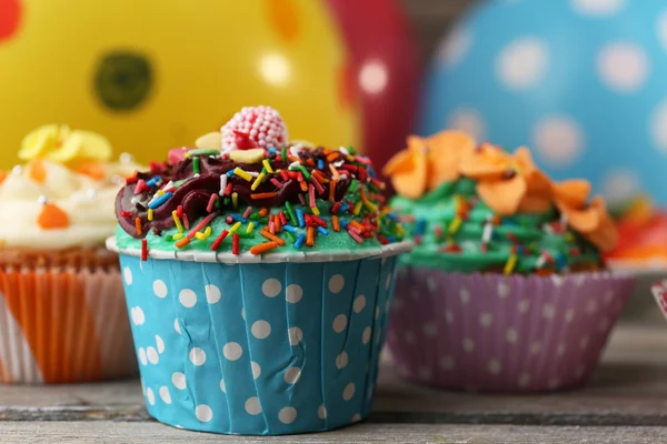 Deliciosos cupcakes de aniversário na mesa em fundo brilhante — Fotografia de Stock