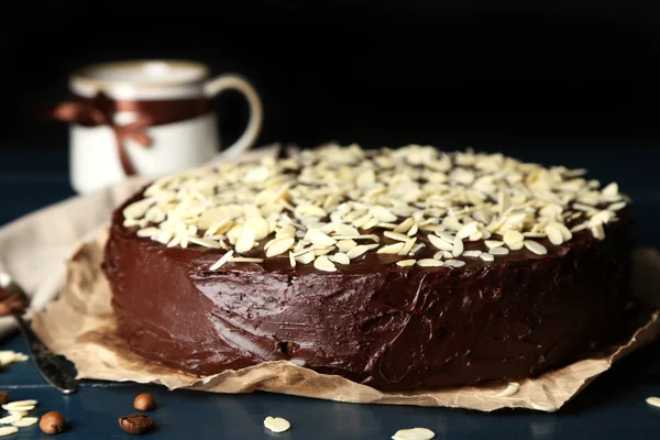 Bolo de chocolate saboroso com amêndoa, na mesa de madeira, no fundo escuro — Fotografia de Stock