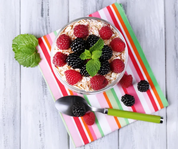 Healthy breakfast - yogurt with  fresh fruit, berries and muesli served in glass jar, on color wooden background — Stock Photo, Image