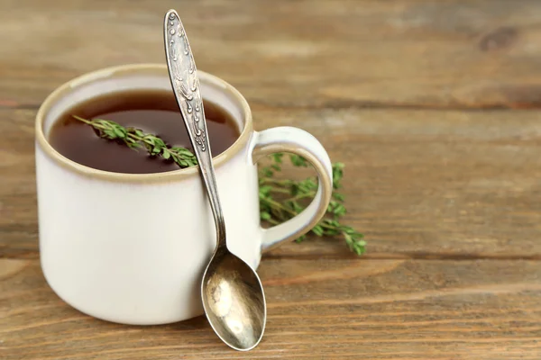 Tasse leckeren Kräutertee mit Thymian auf Holztisch — Stockfoto