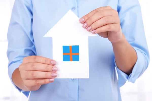 Frau hält Papierhaus auf hellem Hintergrund — Stockfoto