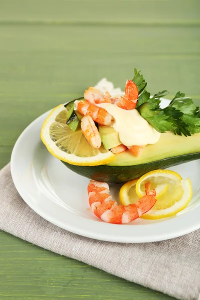 Salada saborosa com camarões e abacate na placa, no fundo de madeira — Fotografia de Stock
