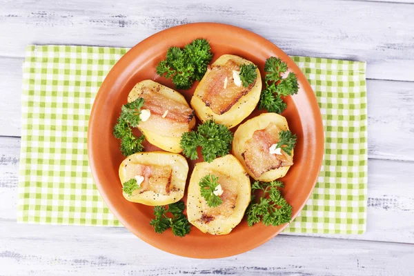 Baked potato with bacon on plate, on wooden background — Stock Photo, Image