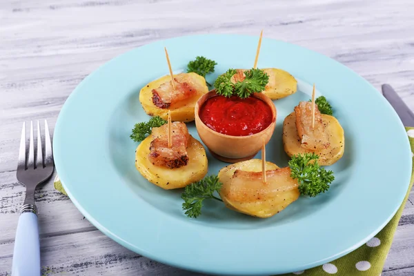 Baked potato with bacon on plate, on wooden background — Stock Photo, Image