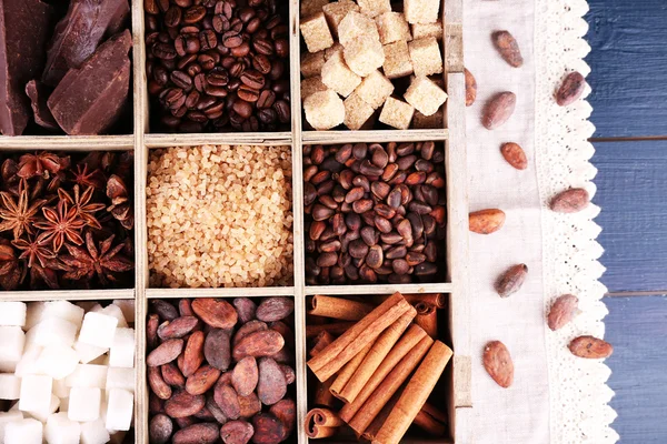 Caja de madera con set de café y granos de cacao, terrones de azúcar, chocolate negro, canela y anís sobre fondo de madera —  Fotos de Stock