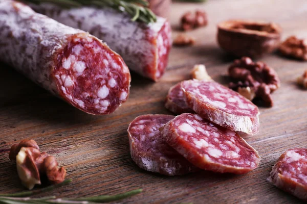 Französische Salami und Walnüsse auf Holzgrund — Stockfoto