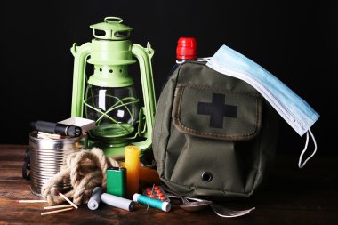 Emergency preparation equipment on wooden table, on dark background clipart