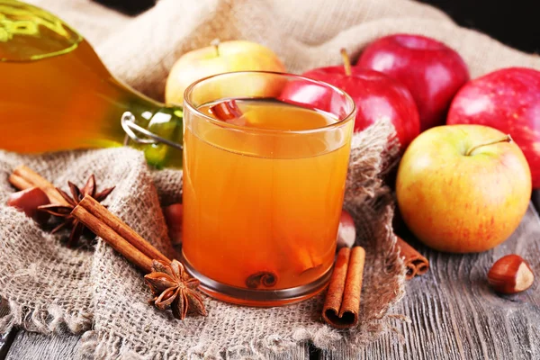 Sidra de manzana con palitos de canela, especias y manzanas frescas sobre fondo de madera — Foto de Stock