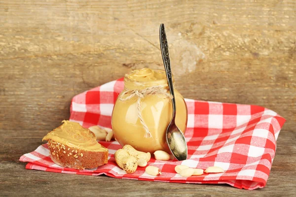 Fresh peanut butter in jar on wooden background — Stock Photo, Image