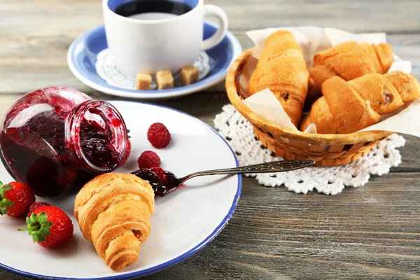 Desayuno con té, mermelada de frambuesa y cruasanes frescos sobre fondo de madera —  Fotos de Stock