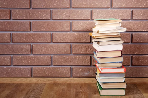 Buku-buku di meja kayu pada latar belakang dinding bata — Stok Foto