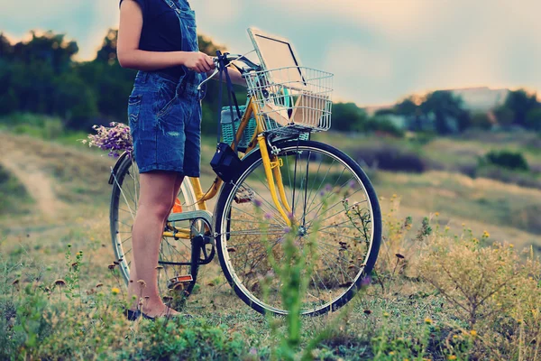 Mujer joven con bicicleta en el prado — Foto de Stock