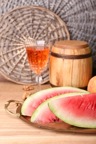 Composição de melancia madura, frutas, vinho rosa em vidro e barril de madeira na mesa de madeira cor, no fundo de tijolos — Fotografia de Stock