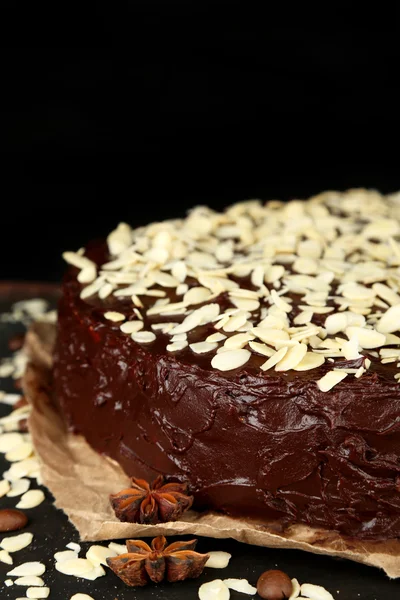 Tasty chocolate cake with almond, on wooden table, on dark background — Stock Photo, Image