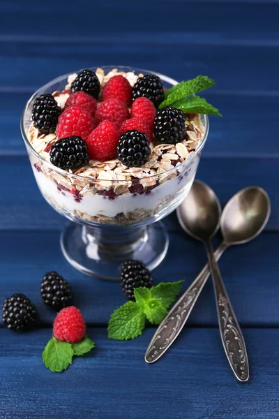 Healthy breakfast - yogurt with  fresh berries and muesli served in glass bowl, on dark color background — Stock Photo, Image