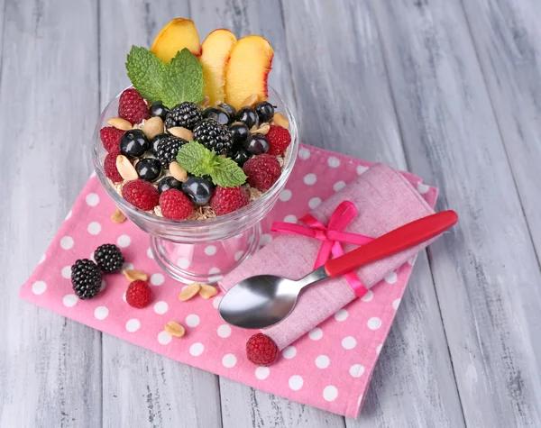 Egészséges - joghurt, friss gyümölcsök, bogyók, müzli, reggeli üvegtál színes fából készült háttér — Stock Fotó