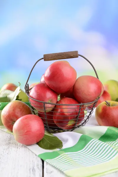 Süße Äpfel im Weidenkorb auf dem Tisch vor hellem Hintergrund — Stockfoto