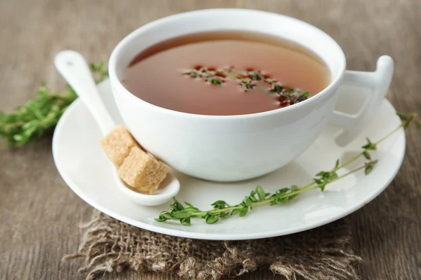 Tazza di gustosa tisana con timo sul tavolo di legno — Foto Stock