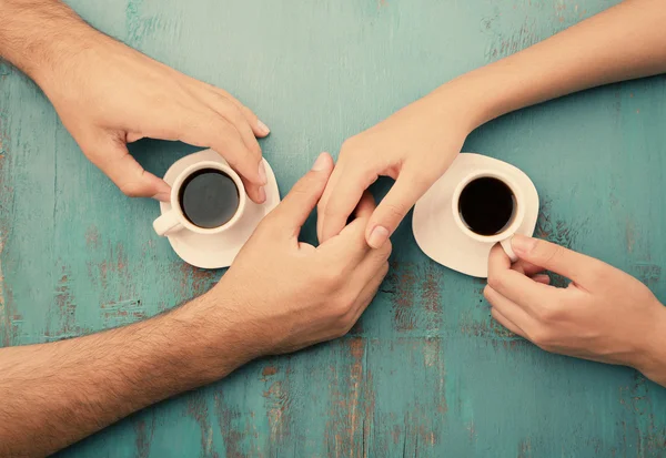 Cangkir kopi dan berpegangan tangan di meja kayu — Stok Foto