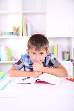 школяр, сидячи на столі в класі