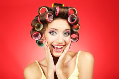 Kırmızı zemin üzerine saç curlers içinde güzel kız