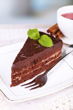 Dantel peçete ve çay doğal zemin üzerine ahşap masa üzerinde plaka üzerinde çikolatalı kek parçası