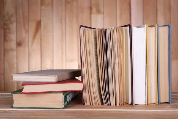 Książki na drewnianym stole na tle ściany drewniane — Zdjęcie stockowe