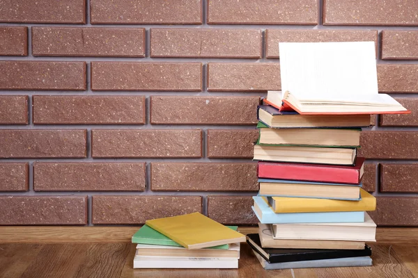 Books on wooden table on brick wall background — Stock Photo, Image