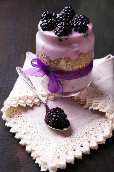 Healthy breakfast - yogurt with  blackberries and muesli served in glass jar, on dark wooden background — Stock Photo, Image