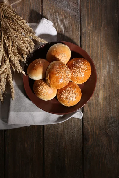 Goda bullar med Sesam på plattan, på trä bakgrund — Stockfoto