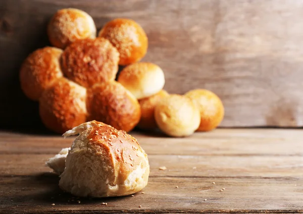 Pães saborosos com gergelim na cor de fundo de madeira — Fotografia de Stock