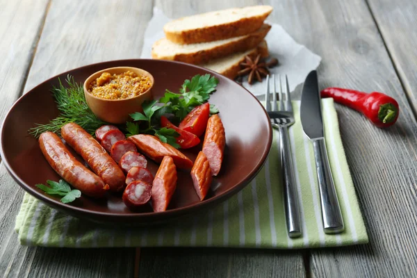 Assortiment de savoureuses saucisses fines sur assiette sur fond en bois — Photo